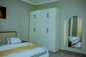 a white bedroom with a bed and a mirror at Obama Apartments in Mbweni