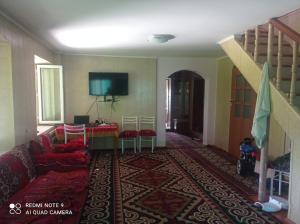 a living room with a couch and a tv at Гостевой дом Izat in Karakol