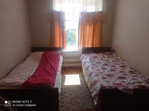 two beds in a small room with a window at Гостевой дом Izat in Karakol