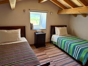 two beds in a room with a window at Casa da Curva in Mendiga
