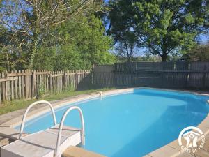 a swimming pool in a backyard with a wooden fence at Le grand gîte de souels in Almayrac