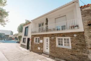 a brick house with a balcony on a street at Houses São Pedro in São João da Pesqueira