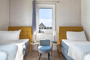 a room with two beds and a chair and a window at Ferienhaus Möwenkoje Olpenitz in Olpenitz