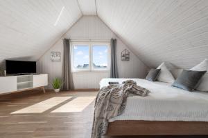 a white bedroom with a bed and a window at Ferienhaus Möwenkoje Olpenitz in Olpenitz