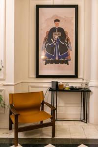 a chair next to a table with a picture on the wall at Hotel Vasanta in Barcelona