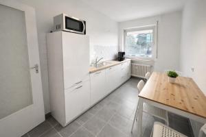 a kitchen with a white refrigerator and a wooden table at Pulheim Living 4 in Pulheim