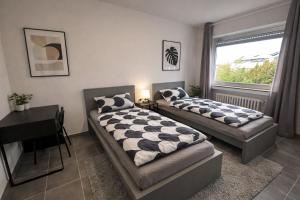 two beds in a room with a desk and a window at Pulheim Living 4 in Pulheim