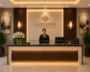 a woman standing behind a counter in a hotel lobby at Hotel La Serene in Agra