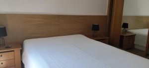 a bedroom with a white bed and a mirror at Apartamento Sol e Mar 1 in Monte Gordo