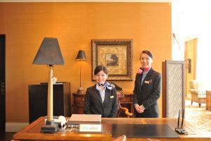 two women in suits standing next to a desk at Forest Hills Garden in Mihara