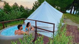 a man and woman sitting in a hot tub with a teepee at Agriturismo La Taverna in Fontanelice