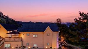 a house with a sunset in the background at Chuncheon Happysday Pet-Friendly Pension in Chuncheon +2 photos