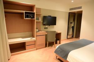 a hotel room with a bed and a desk and a television at Royalton Hyderabad Abids in Hyderabad