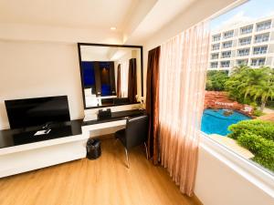 a hotel room with a desk and a large window at Nova Platinum Hotel in Pattaya South