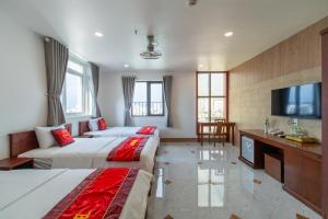 a hotel room with two beds and a flat screen tv at Apogee Hotel in Ho Chi Minh City