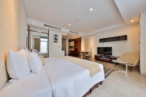 a bedroom with a large white bed and a television at SILA Urban Living in Ho Chi Minh City