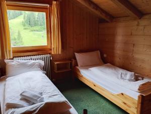 two beds in a room with a window at Rifugio Plan Boè in Livinallongo del Col di Lana