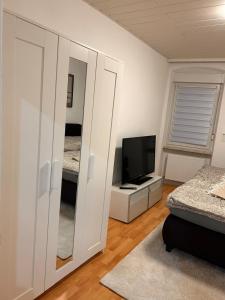 a bedroom with a tv and a white closet at Ferienwohnung Noela in Sankt Ingbert