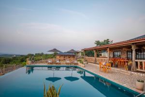 a swimming pool with tables and chairs and a building at Acacia Wilderness Mweya in Kasese