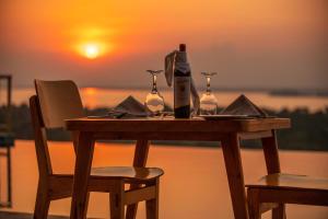 a table with a bottle of wine and two glasses at Acacia Wilderness Mweya in Kasese