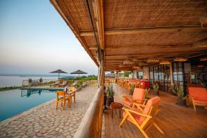 a resort with a pool and tables and chairs at Acacia Wilderness Mweya in Kasese