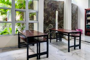 two tables and chairs in front of a window at Dprof Exclusive Guesthouse Semarang RedPartner in Jatingaleh