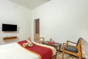 a bedroom with a bed and a tv and chairs at De Asian Resort in Pondicherry
