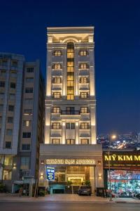 a tall white building with a sign in front of it at Apogee Hotel in Ho Chi Minh City