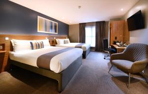 a hotel room with two beds and a desk and a chair at Travelodge Plus Galway in Galway +18 photos