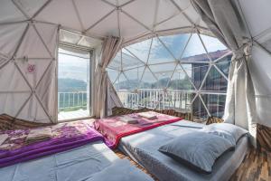 two beds in a room with a large window at Mon P Monjam in Mon Jam