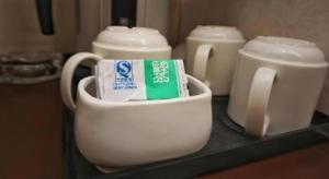ein weißer Becher mit einer Tube Zahnpasta und einem Behälter Milch in der Unterkunft Oriental Lander Hotel in Hongkong