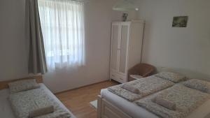 a bedroom with two beds and a dresser and a window at Éva Apartmanház 2 in Csopak