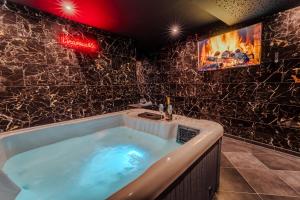 a jacuzzi tub in a bathroom with black marble walls at L'inavouable Love-room Jacuzzi in Marquise