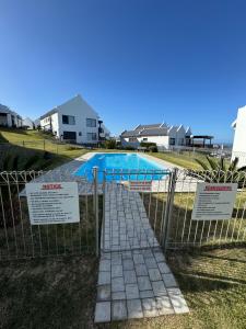 a fence with signs in front of a swimming pool at Oceanview Stays in Great Brak River