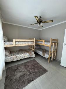 a room with three bunk beds and a ceiling fan at Oceanview Stays in Great Brak River