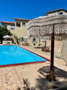 a pool with an umbrella and chairs next to a building at Samos Panorama Hills in Pythagoreio