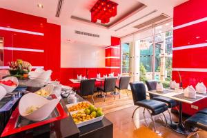 a restaurant with red walls and tables and chairs at Nova Platinum Hotel in Pattaya South