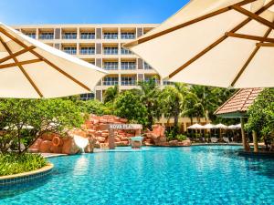 a pool at a resort with two umbrellas at Nova Platinum Hotel in Pattaya South
