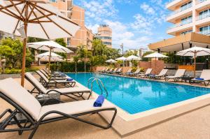 a pool with lounge chairs and umbrellas at a hotel at Nova Platinum Hotel in Pattaya South