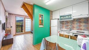 a kitchen with a table and a green wall at Geoje Araon Pension in Geoje