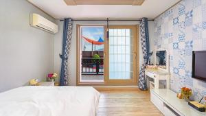 a bedroom with a bed and a view of a balcony at Geoje Araon Pension in Geoje