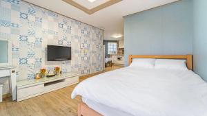 a bedroom with a bed and a tv on a wall at Geoje Araon Pension in Geoje