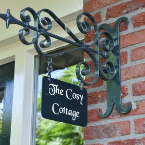 a sign that reads the cosy cottage attached to a building at The Cosy Cottage - Comfort Sauna & Hot Tub in Private Garden in Zeewolde
