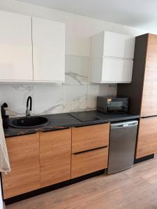 a kitchen with white cabinets and a sink at Bright & Brand New Appartment in Liepāja