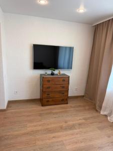 a living room with a tv and a wooden dresser at Bright & Brand New Appartment in Liepāja