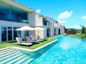 a house with a swimming pool with chairs and umbrellas at KAYATSUMA OKINAWA Hotel&Resort in Nakijin