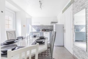 a white kitchen with a dining table with black plates at Hello Flat - Maison de ville près de Paris in Athis-Mons