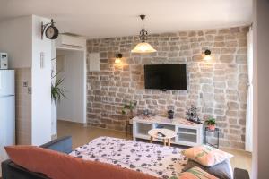 a living room with a brick wall with a tv at APARTMANI Mirona - Tučepi in Tučepi