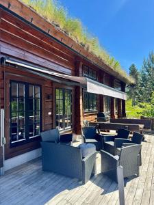 a log cabin with chairs and tables on a deck at Koslig helårs hytte in Heimdal