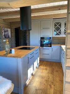 a kitchen with white cabinets and a wooden floor at Koslig helårs hytte in Heimdal